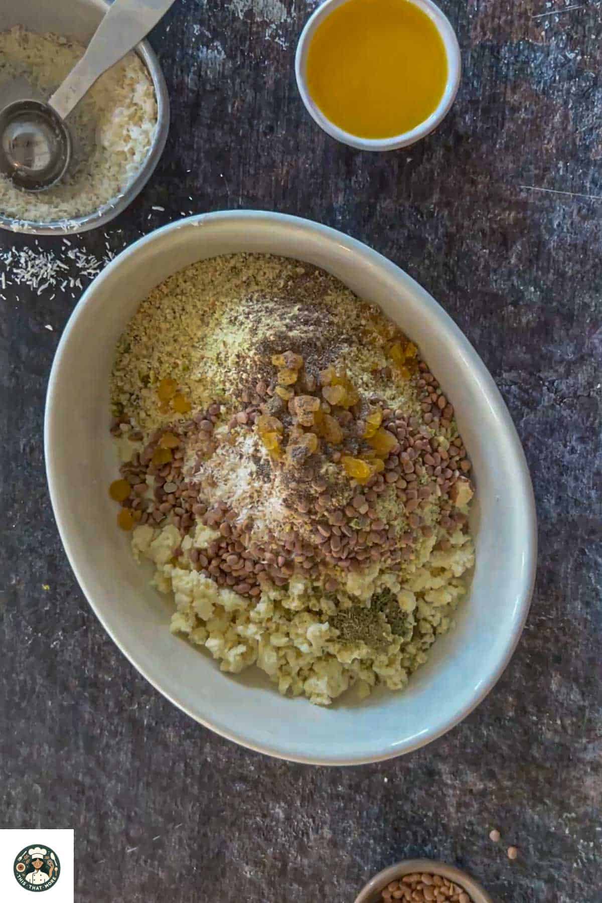 Image showing khoya, coconut powder, powdered sugar, nuts powder, raisins, chironji, cardamom powder, and fennel seeds powder are added in a white bowl