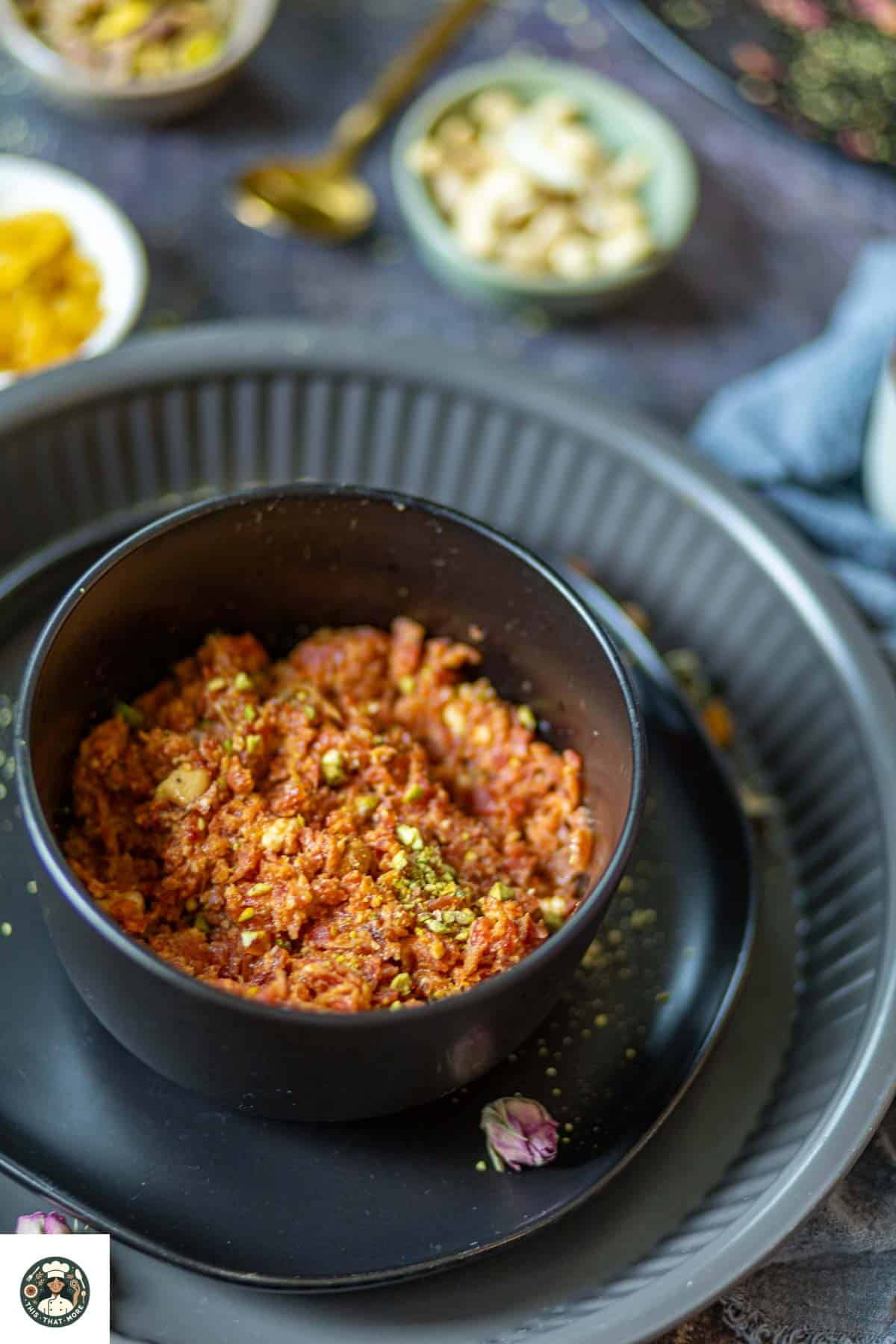 This easy carrot halwa recipe served in a black bowl which is garnished with pistachios.