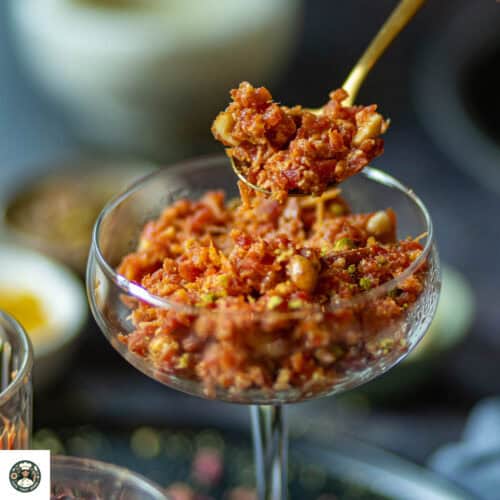 A close up shot of carrot halwa with khoya in a spoon.