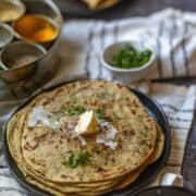 Image showing dollop of butter on stack of gobi parathas.