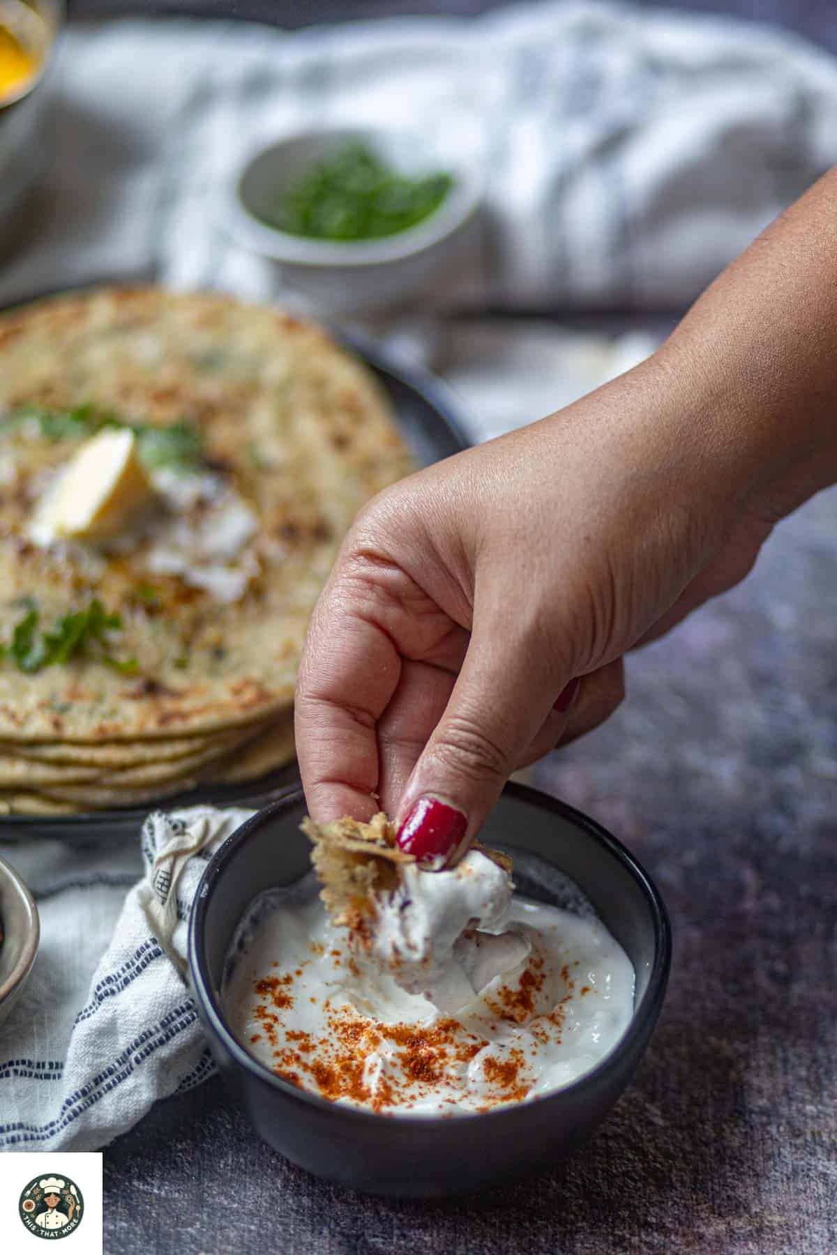 Dipping gobi ka paratha in yogurt.