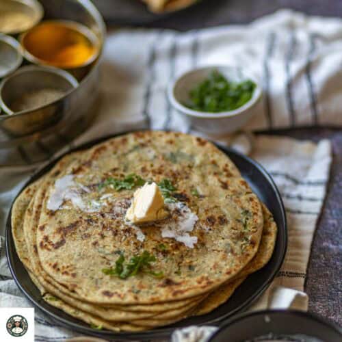 Image showing dollop of butter added to stack of gobi parathas.