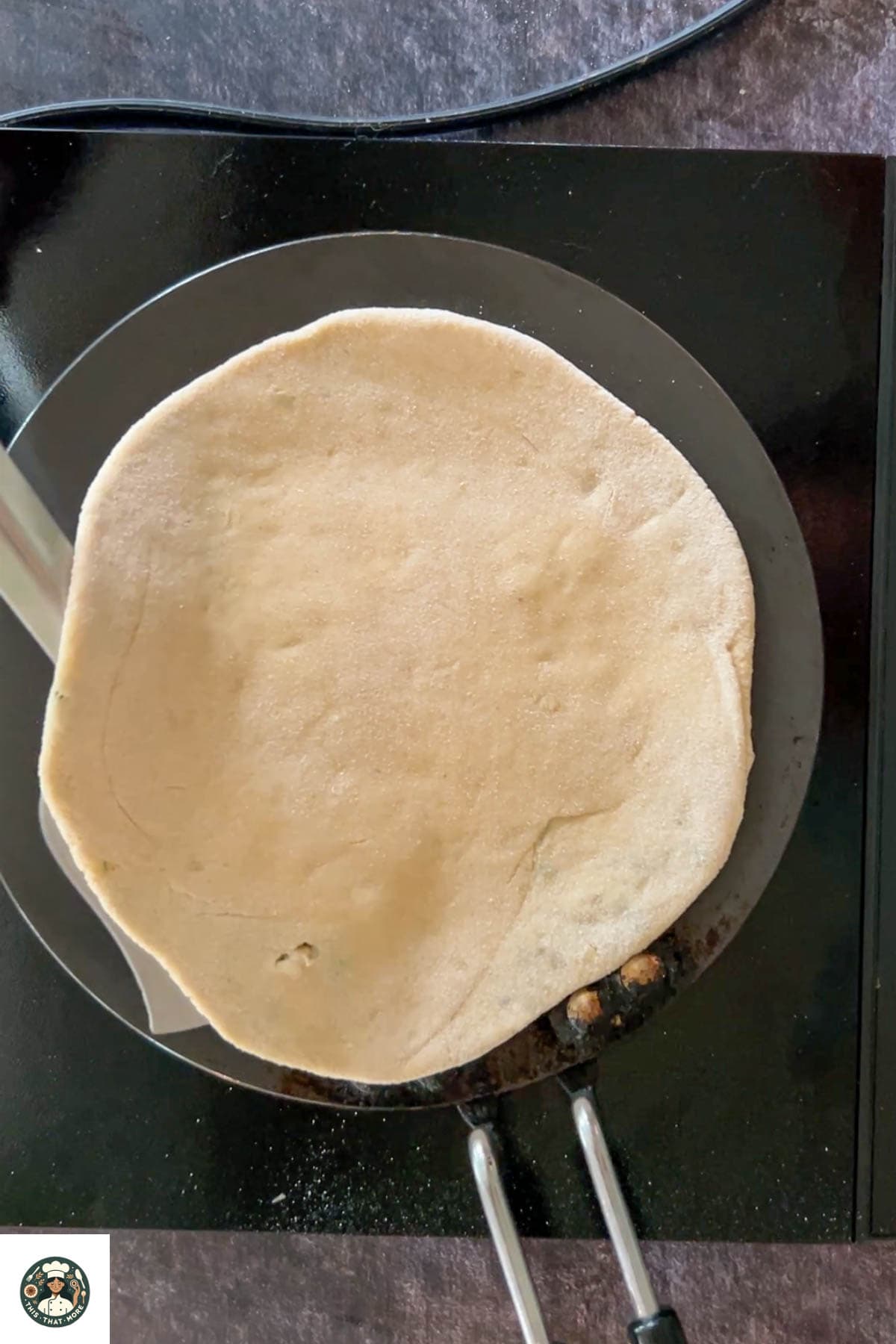 Place the rolled paratha on the hot pan. Cook one side for a few seconds, flip, and apply ghee or oil on both sides.
