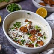 Smashed potato salad served in a white bowl.