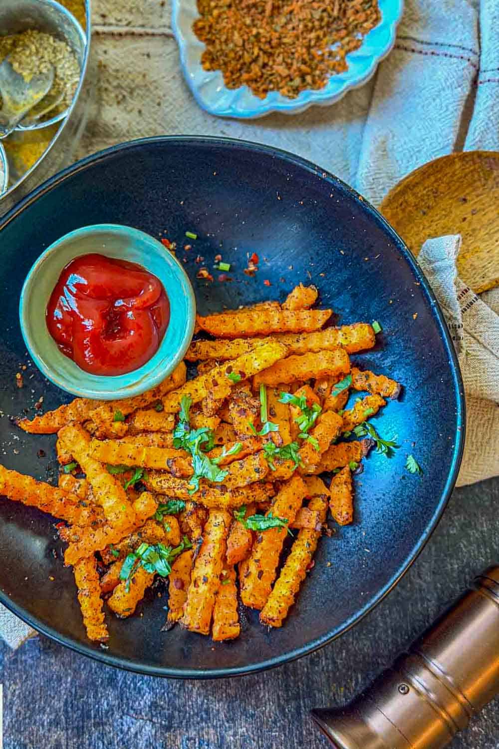 Seasoned crinkle-cut butternut squash fries served in a black bowl with ketchup.