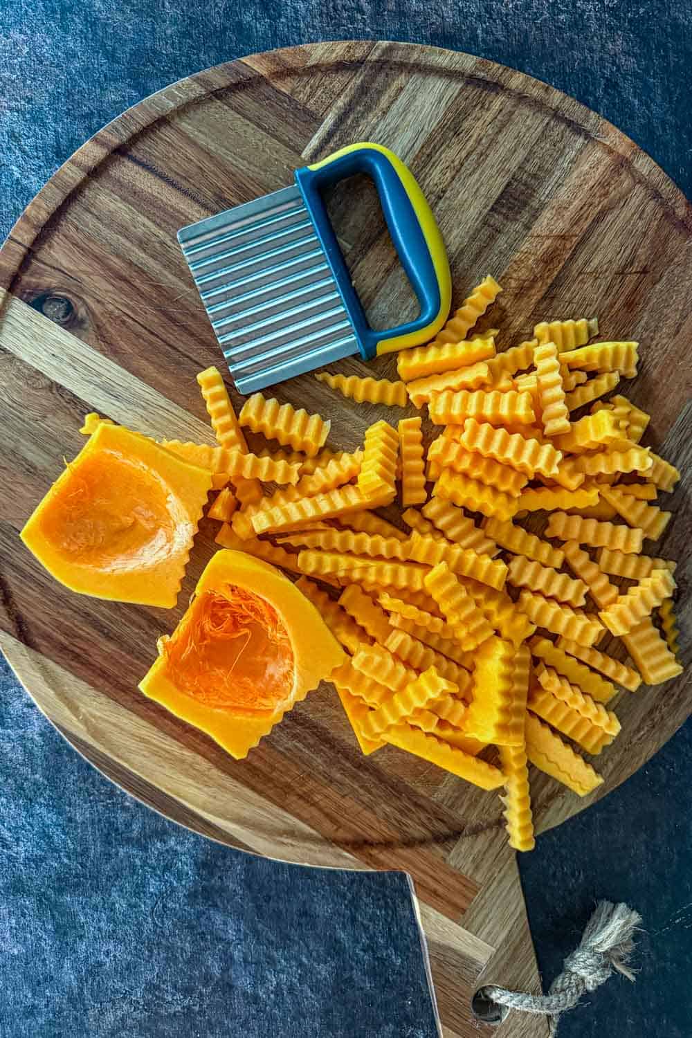 Crinkle-cut butternut squash pieces on a cutting board with a wavy crinkle cutter.