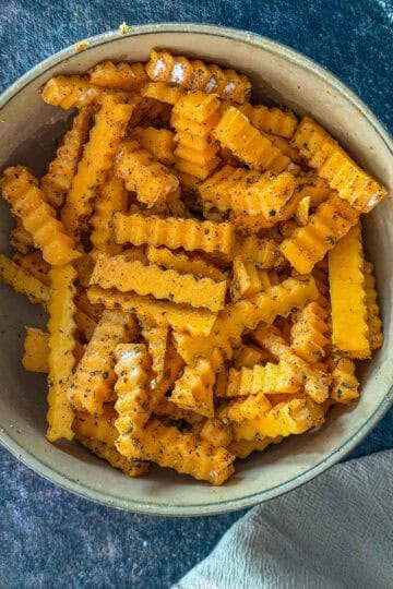 Seasoned butternut squash fries tossed and ready to air fry in a mixing bowl.