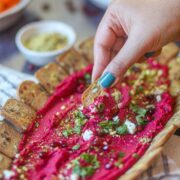 Cracker dipped into creamy beetroot hummus.