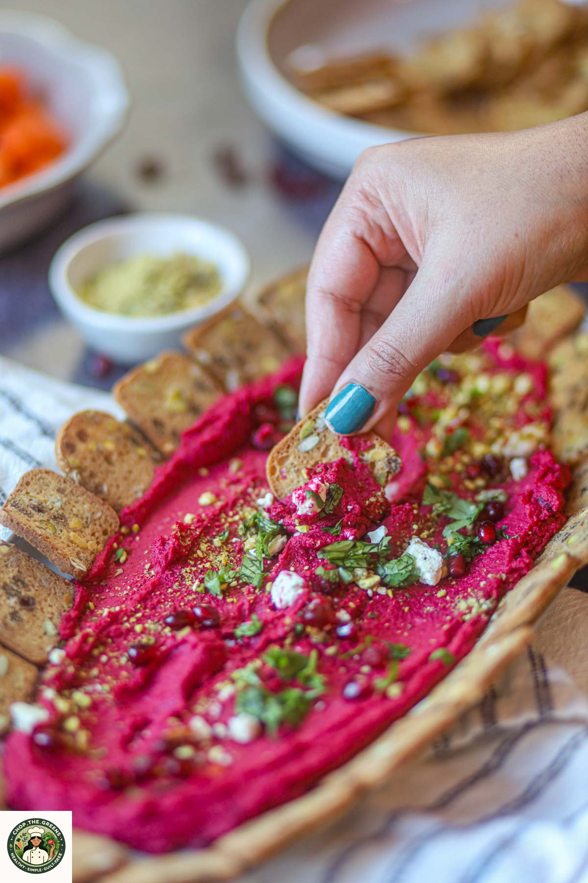 Cracker dipped into creamy beetroot hummus.