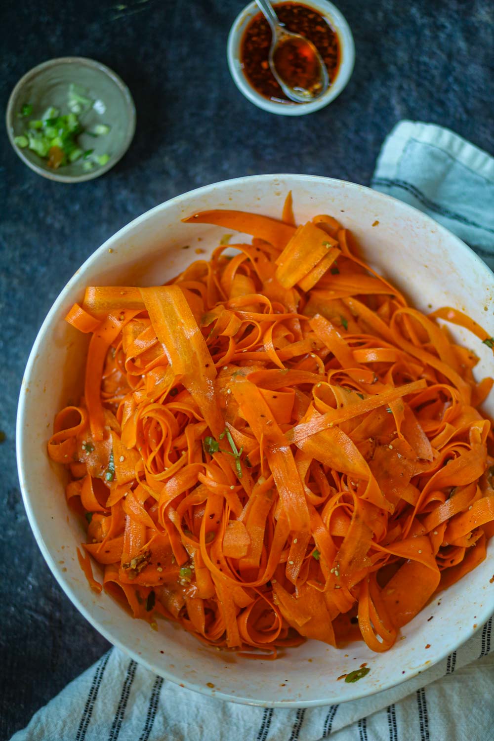Top view of carrot ribbon salad with dressing ingredients in background.