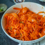 Fresh carrot ribbon salad in a white bowl with herbs and light dressing.