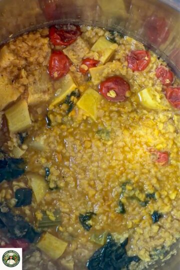 Cooked lentil dal soup with visible tomatoes and vegetables.
