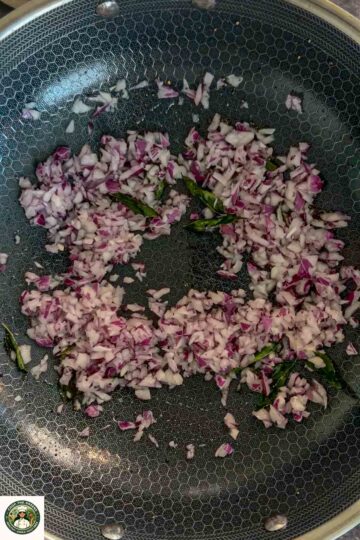 Chopped onions and curry leaves sautéing in a pan for masala oats.