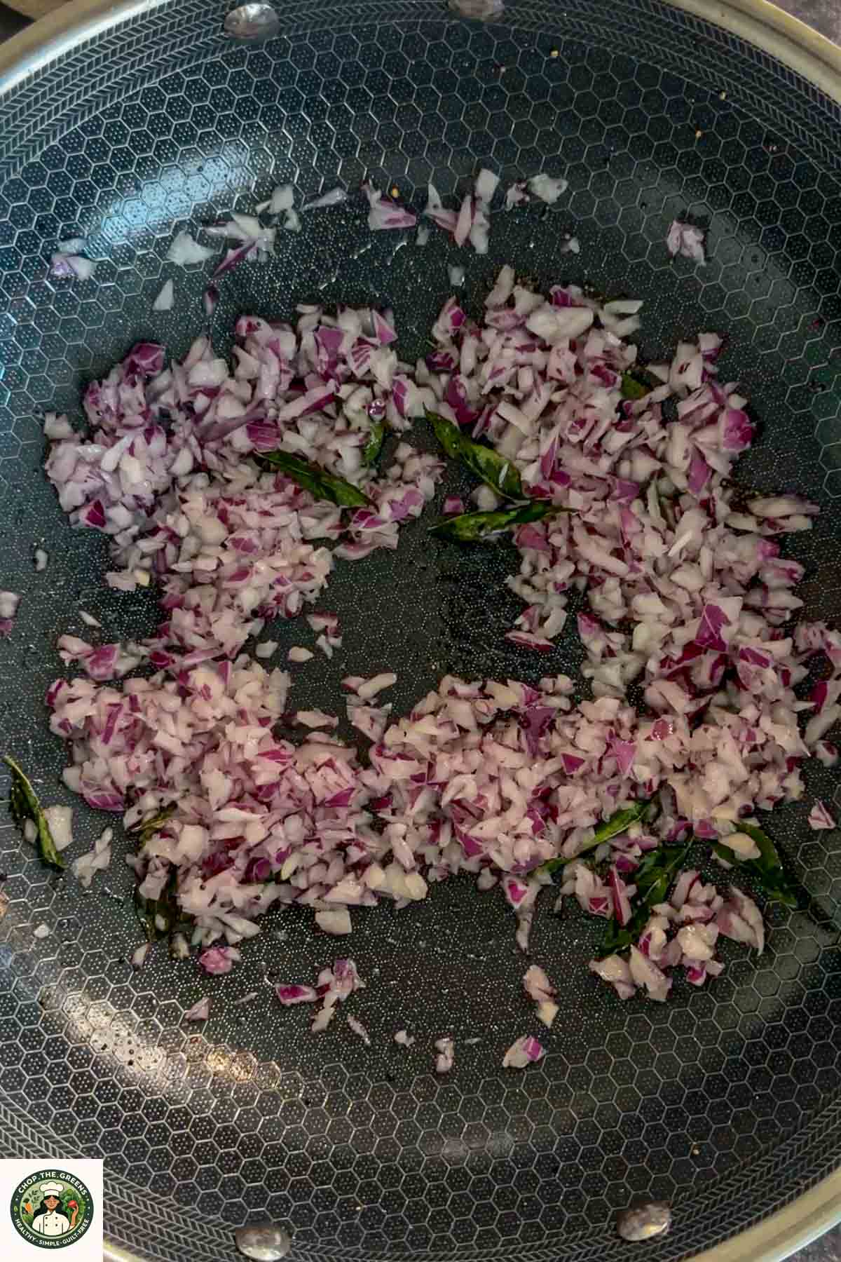Chopped onions and curry leaves sautéing in a pan for masala oats.
