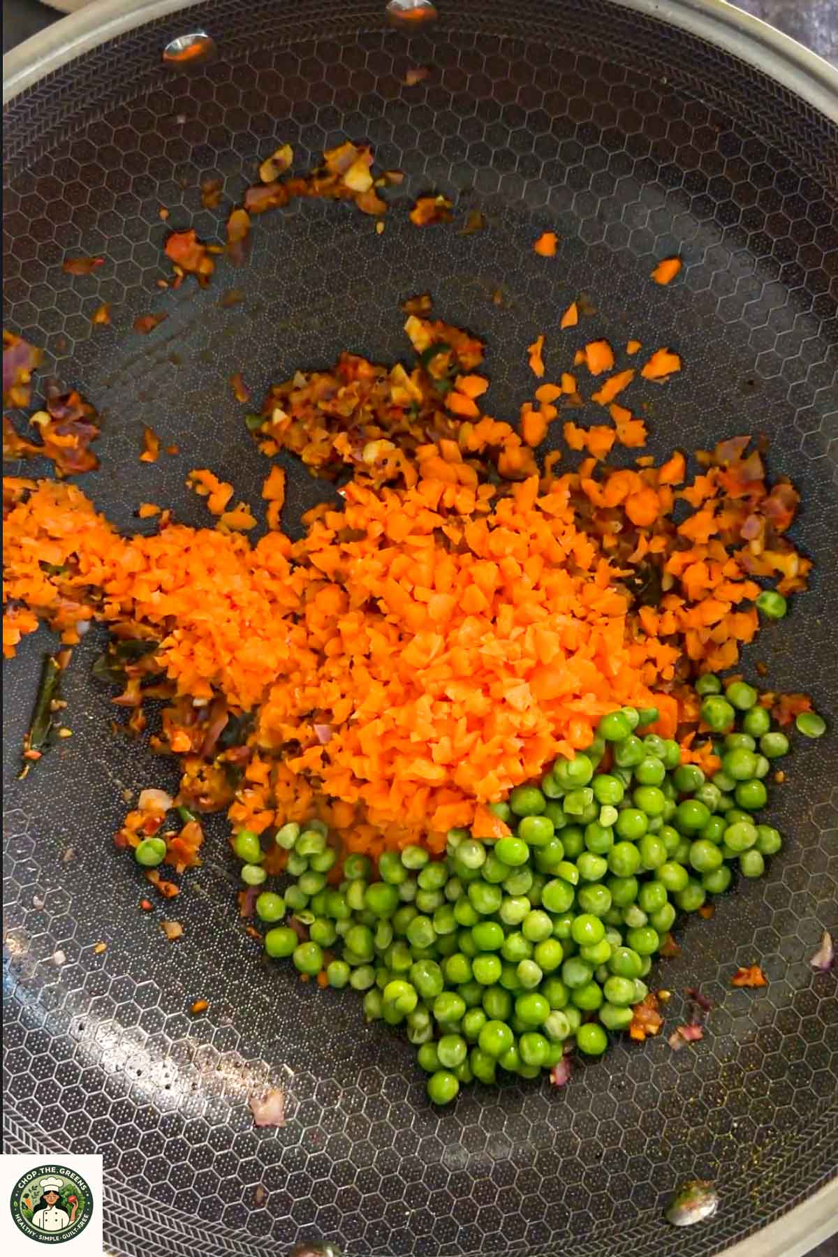 Carrots and green peas added to sautéed onions for masala oats.