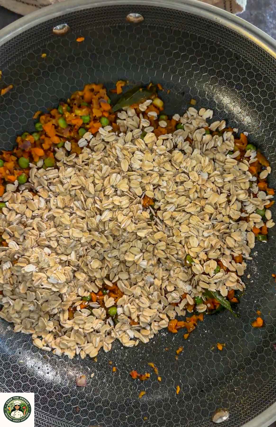 Rolled oats added to vegetables while making masala oats.