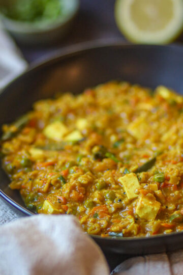 Cooking masala oats with vegetables in a pan.