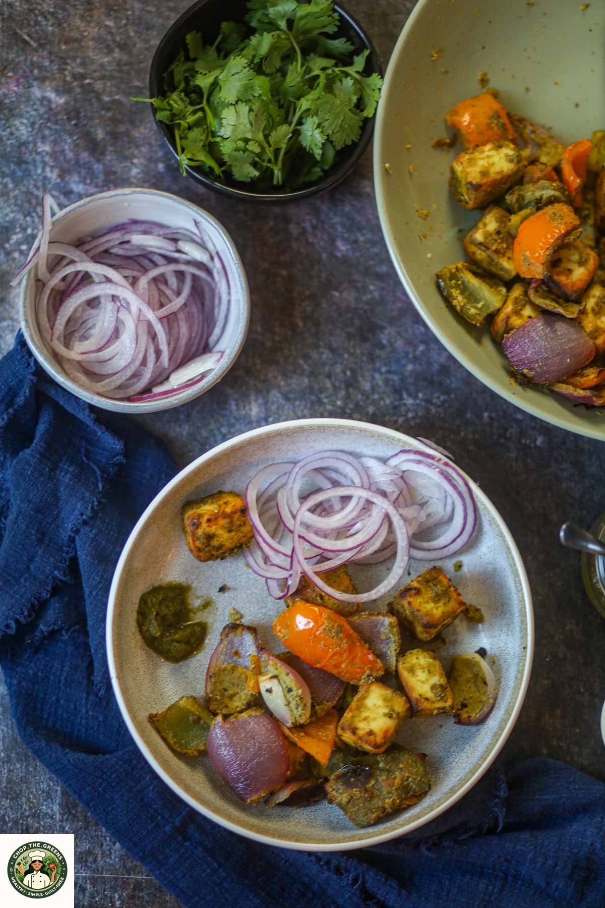 Air fryer hariyali paneer tikka served with sliced onions and green chutney.