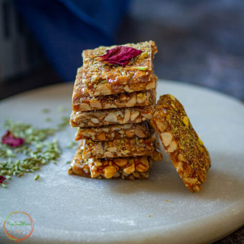 Stacked peanut chikki squares made with jaggery and roasted peanuts.