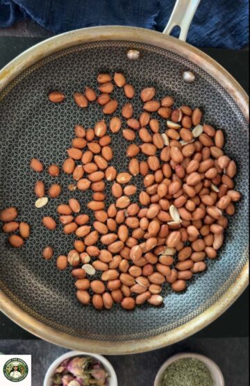 Roasting raw peanuts in a pan for peanut gajak (chikki).
