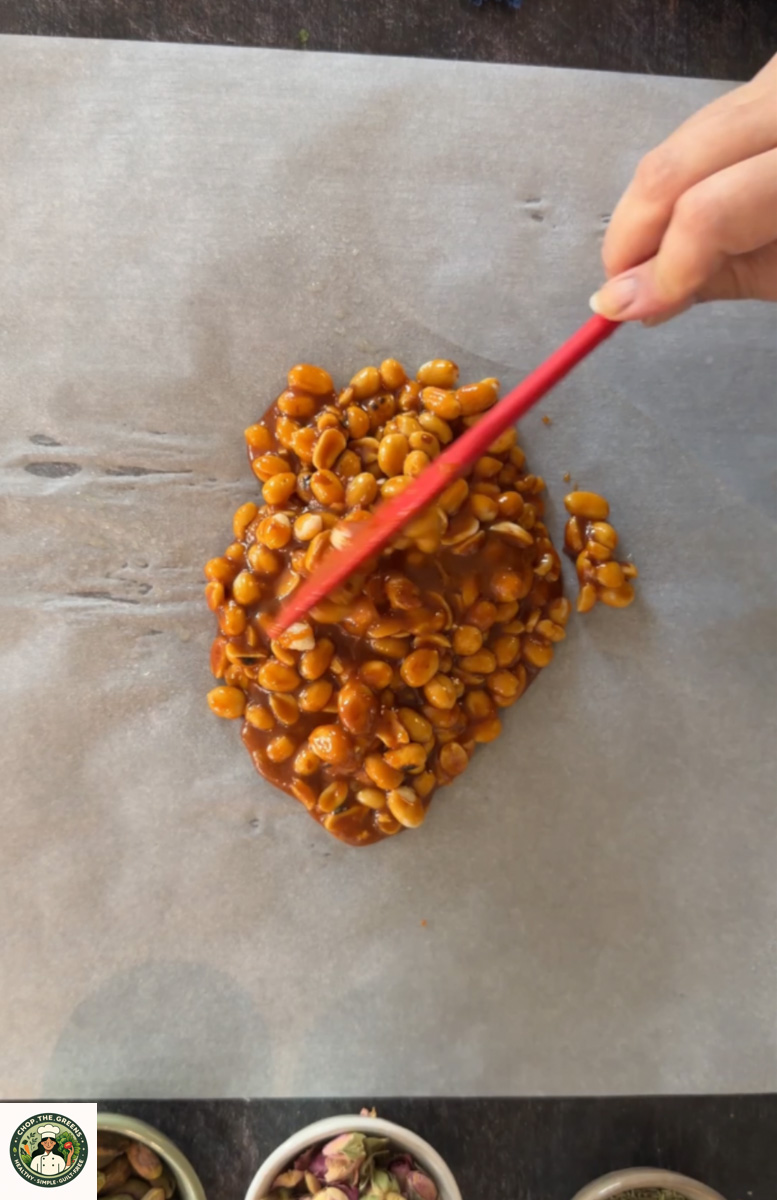 Spreading peanut jaggery mixture on parchment paper.