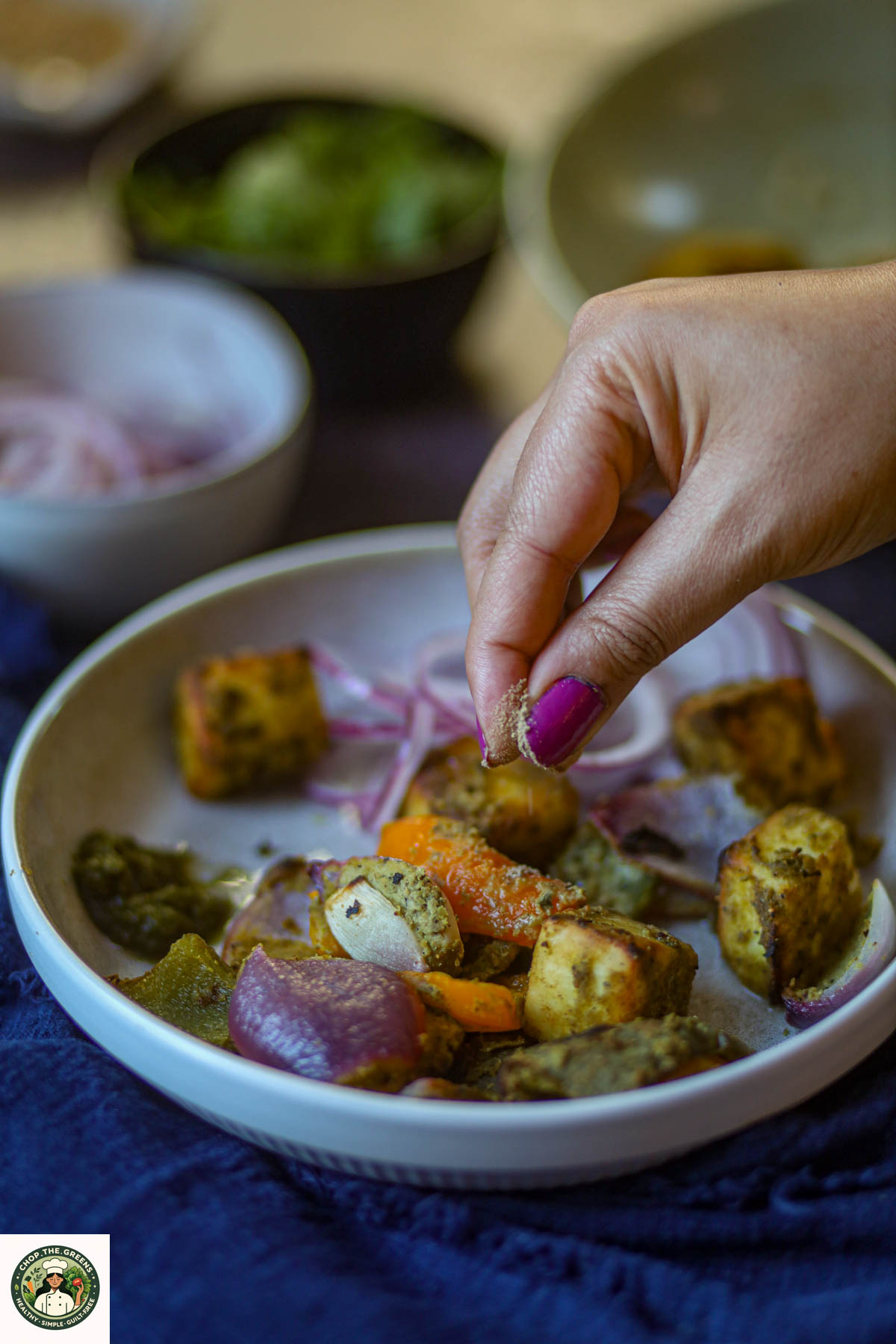 Seasoning being added to hariyali paneer tikka before serving.