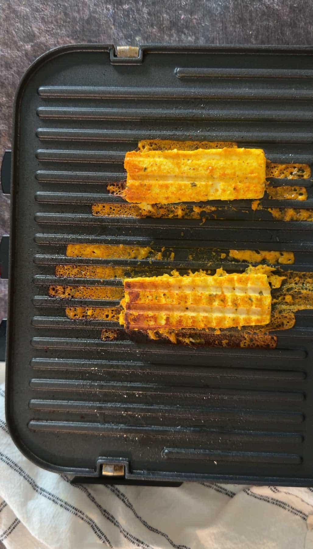 Paneer tikka grilling on stovetop grill pan.