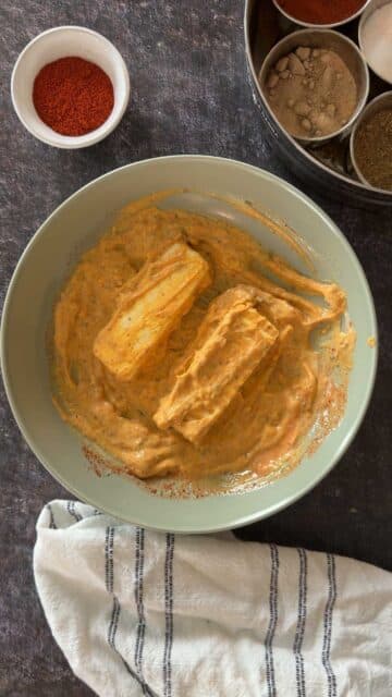 Paneer cubes coated in tikka marinade before grilling.