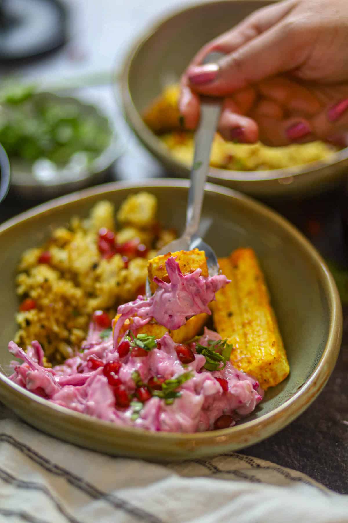 Spoonful of paneer tikka with beetroot raita from high protein bowl.