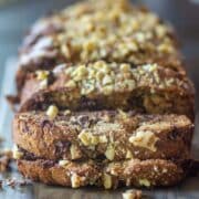 Healthy banana bread loaf topped with chopped nuts and chocolate chips.