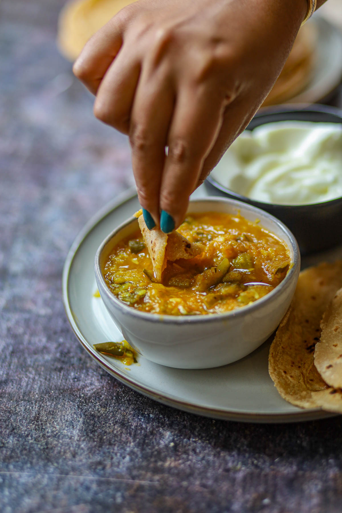 Piece of tofu roti dipped into vegetable curry.