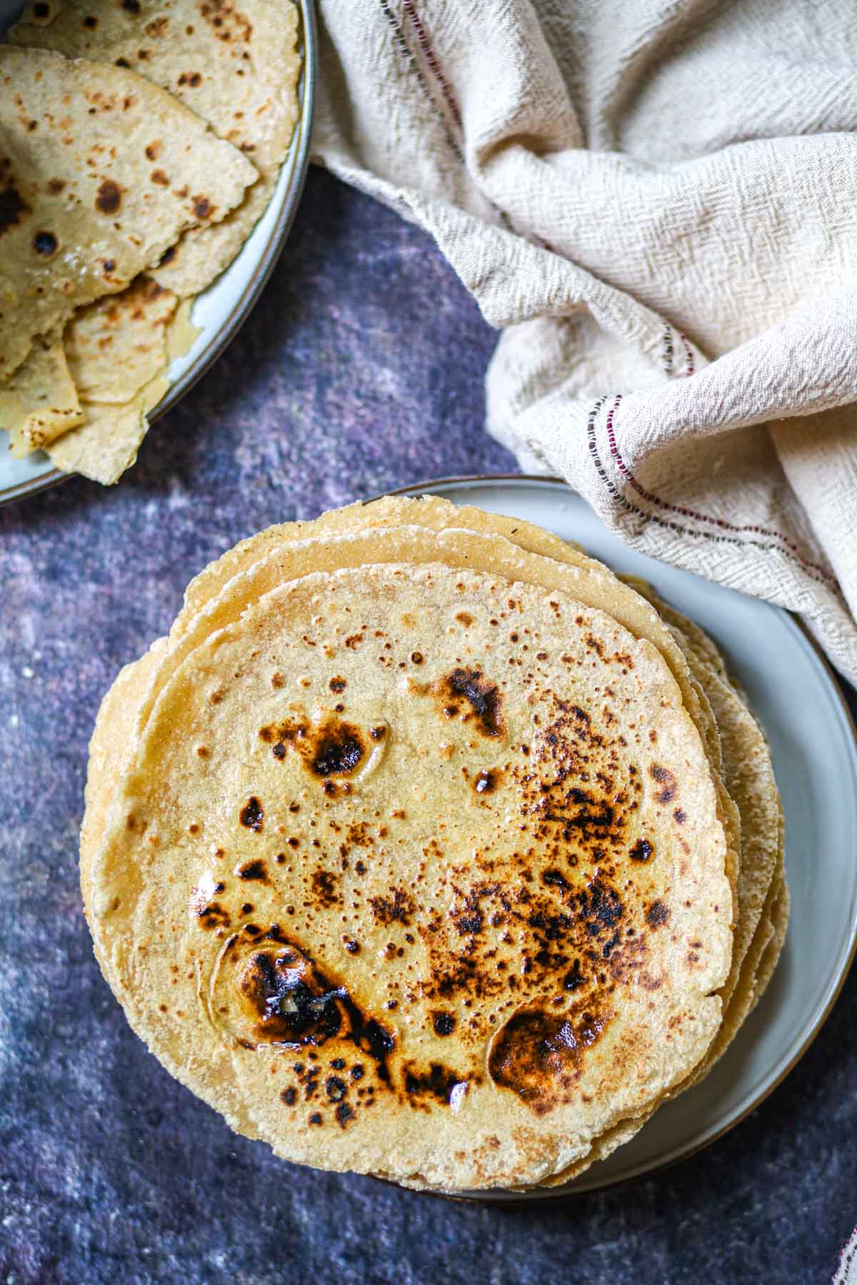 Soft tofu roti on a plate with folded rotis in the background.