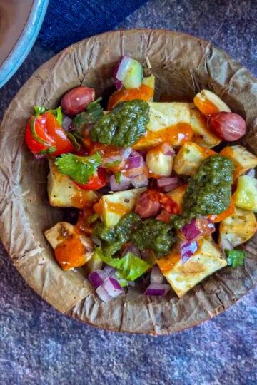 Sweet potato chaat topped with vegetables, chutneys and peanuts.