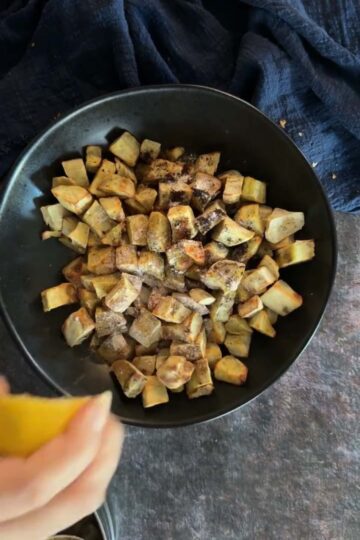 Air-fried sweet potatoes being seasoned with spices and lemon.