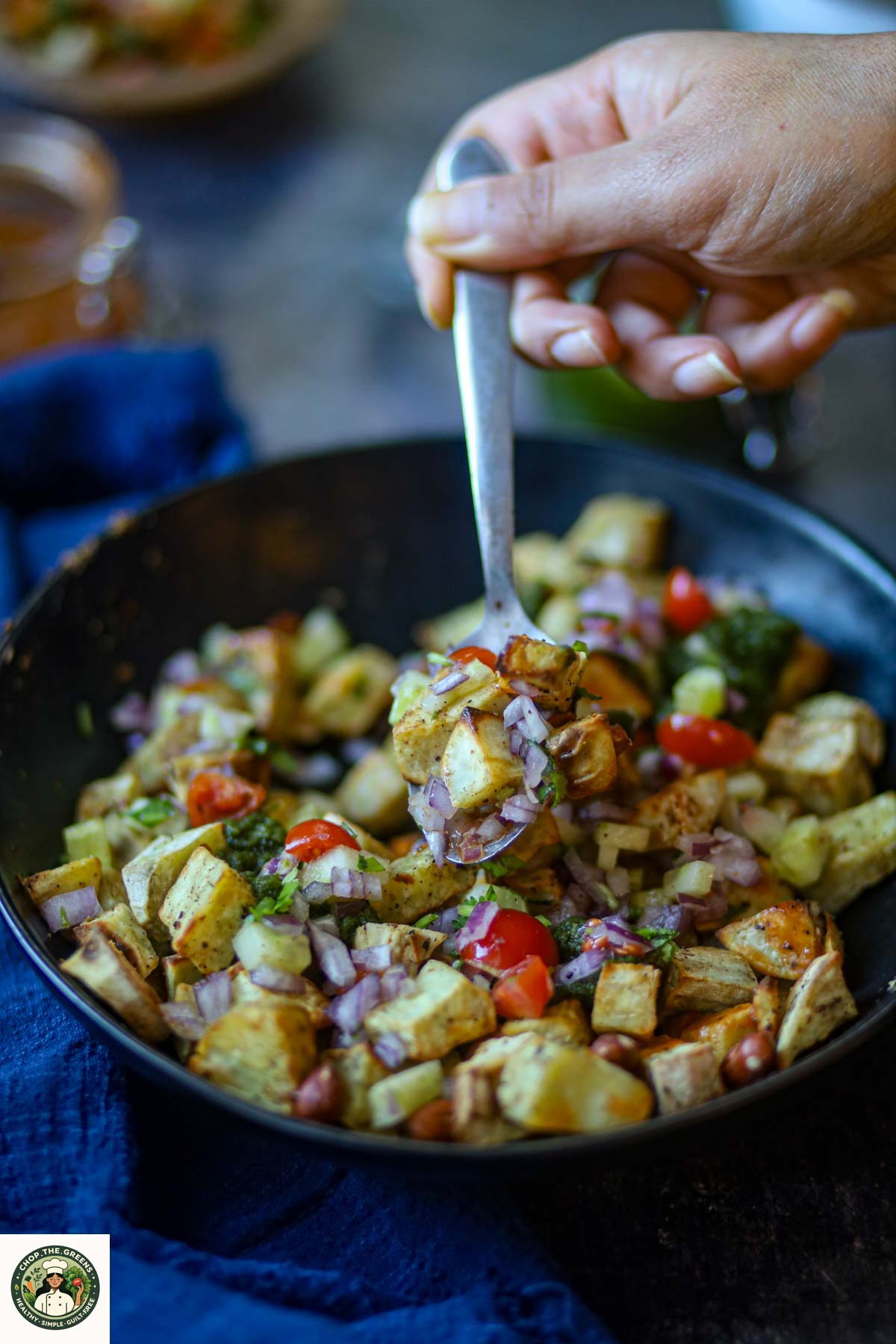 Spoon lifting sweet potato chaat with vegetables and chutney.
