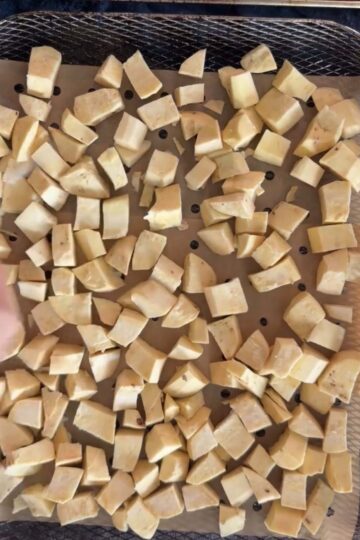 Sweet potato cubes arranged in an air fryer basket.